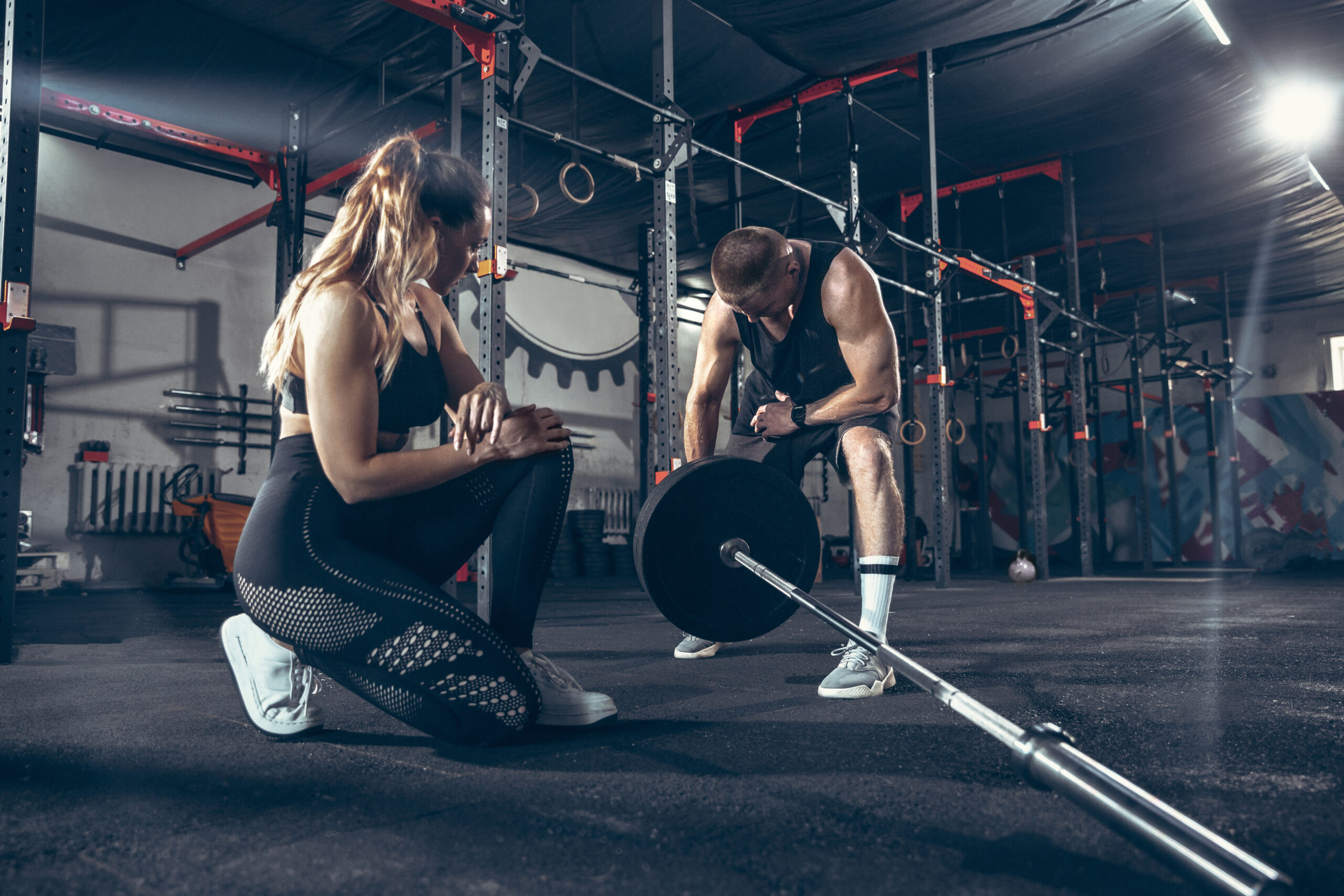 Athletic man and woman with a dumbbells training and practicing in gym. Concept of sport, healthy lifestyle, wellbeing.